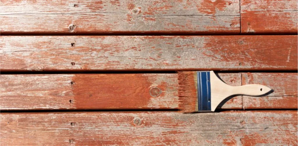 brush loaded with stain on outdoor wooden cedar for resurfacing the home deck